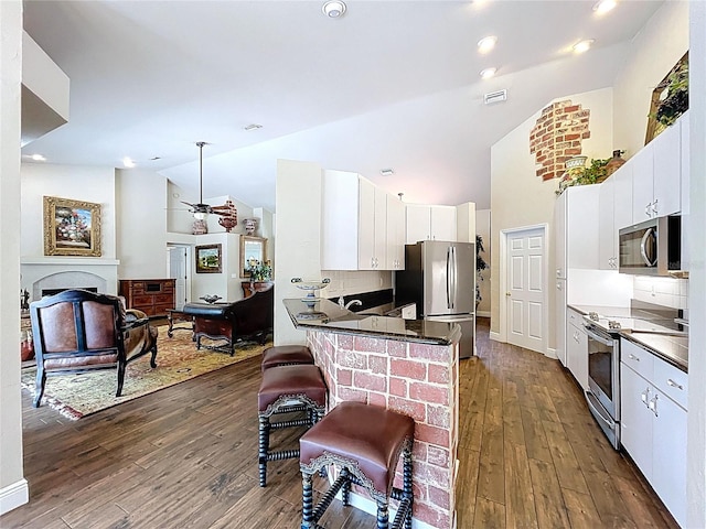 5058 Westlake Blvd, Dade City, FL 33523 - kitchen with stainless steel appliances, dark wood-style floors, dark countertops, a ceiling fan, and high vaulted ceiling
