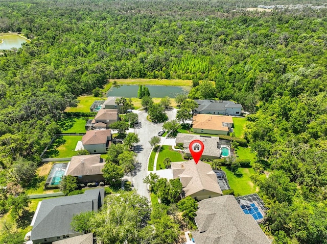 drone / aerial view featuring a forest view, a residential view, and a water view