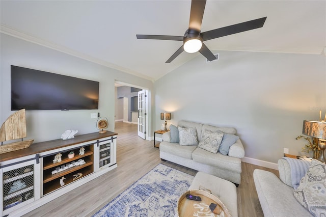 living room featuring ornamental molding, wood finished floors, baseboards, a ceiling fan, and vaulted ceiling