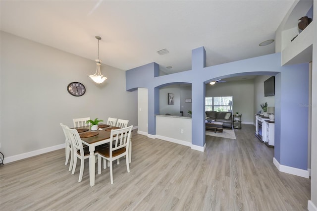 dining area with visible vents, arched walkways, baseboards, and light wood-type flooring