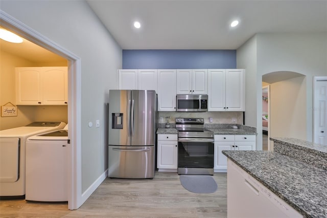 kitchen with light wood-style floors, white cabinets, separate washer and dryer, arched walkways, and stainless steel appliances