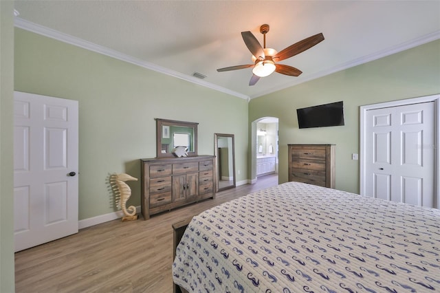 bedroom featuring visible vents, ornamental molding, wood finished floors, baseboards, and arched walkways