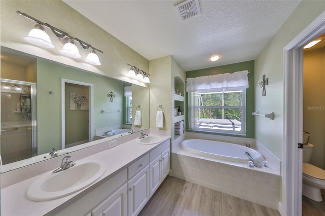 bathroom with a sink, a textured ceiling, a bath, and toilet