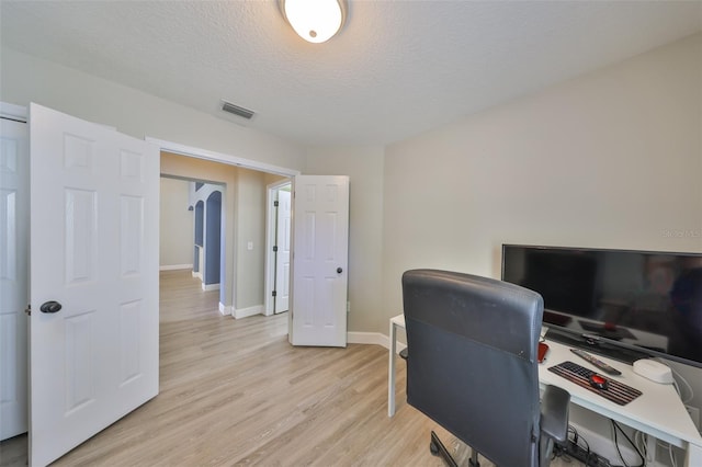 office area featuring a textured ceiling, visible vents, baseboards, and light wood-style floors