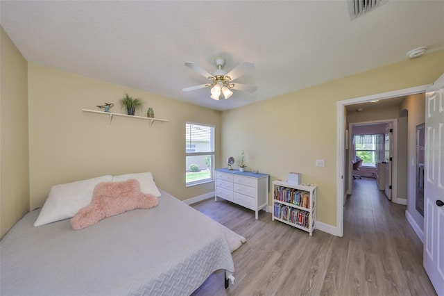 bedroom featuring baseboards, ceiling fan, wood finished floors, and visible vents