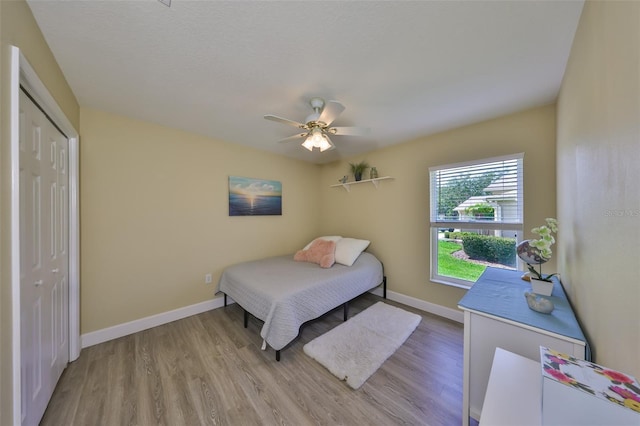 bedroom featuring a closet, baseboards, ceiling fan, and wood finished floors