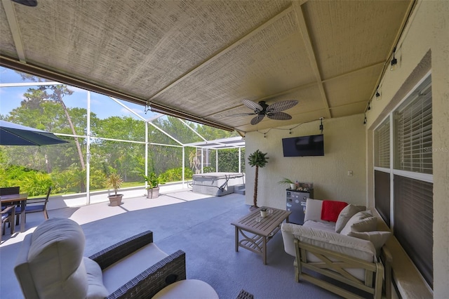 view of patio / terrace with a ceiling fan, outdoor lounge area, a hot tub, and glass enclosure