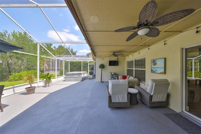 view of patio with a hot tub, ceiling fan, and glass enclosure