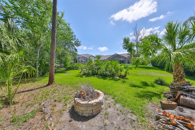view of yard featuring glass enclosure and an outdoor fire pit