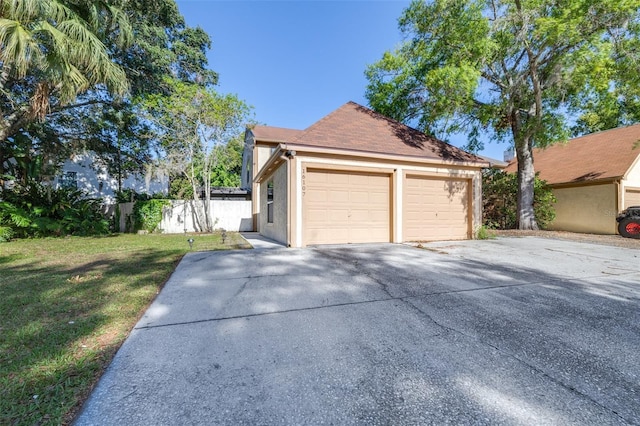 view of front of property with driveway, a garage, fence, a front lawn, and stucco siding