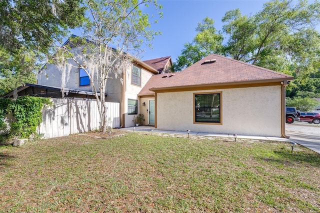 back of property featuring a yard and stucco siding