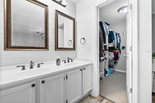 full bath featuring double vanity, a sink, and a walk in closet