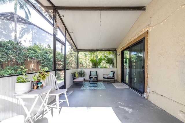 sunroom / solarium featuring beamed ceiling, plenty of natural light, and outdoor lounge area