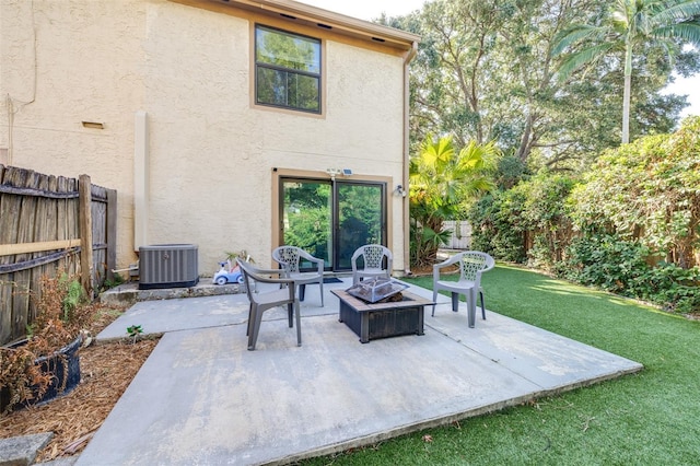 back of property featuring cooling unit, a fenced backyard, an outdoor fire pit, a yard, and stucco siding