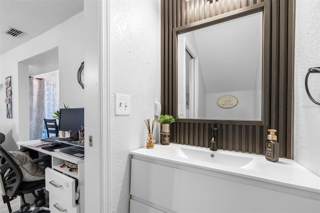 bathroom with a textured wall, visible vents, and vanity
