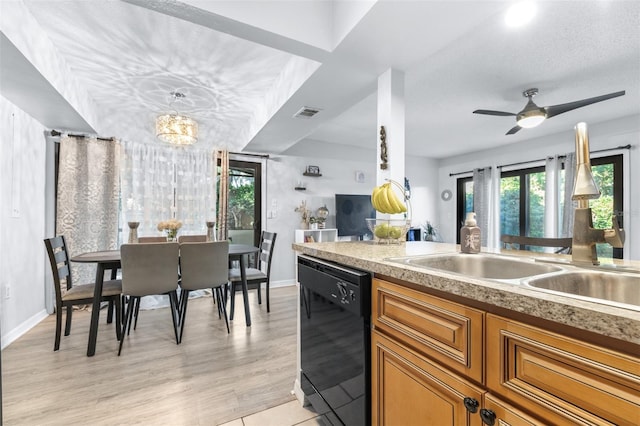 kitchen featuring brown cabinets, light countertops, ceiling fan with notable chandelier, black dishwasher, and visible vents