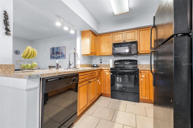 kitchen with a sink, light countertops, black appliances, and a peninsula