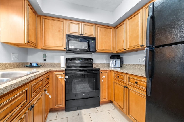 kitchen with light countertops, brown cabinets, light tile patterned floors, and black appliances
