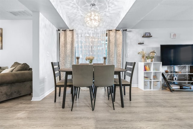 dining space with baseboards, a notable chandelier, wood finished floors, and visible vents