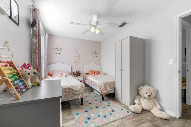 bedroom featuring visible vents, a closet, wood finished floors, a textured ceiling, and a ceiling fan