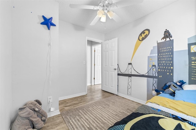 bedroom featuring baseboards, a textured ceiling, ceiling fan, and wood finished floors