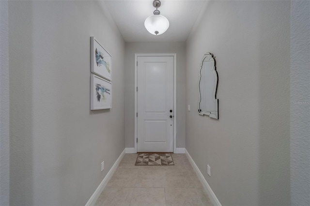 doorway featuring light tile patterned floors and baseboards