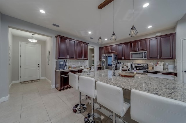 kitchen with decorative backsplash, visible vents, hanging light fixtures, light stone countertops, and stainless steel appliances