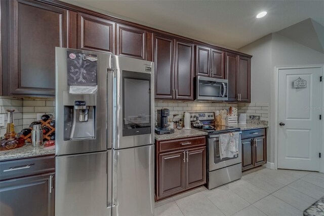 kitchen with decorative backsplash, light tile patterned floors, light stone countertops, and stainless steel appliances
