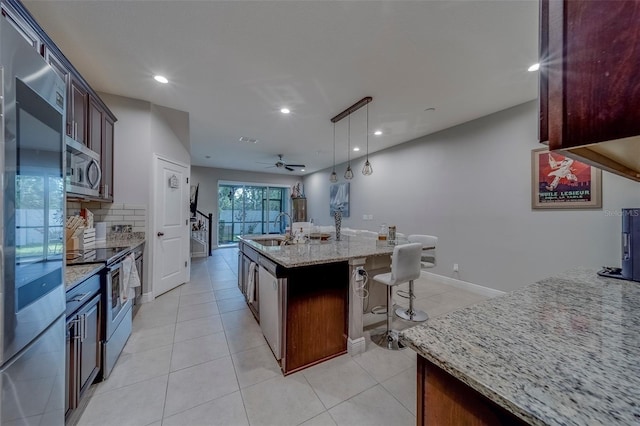 kitchen featuring light stone countertops, appliances with stainless steel finishes, a sink, recessed lighting, and decorative backsplash