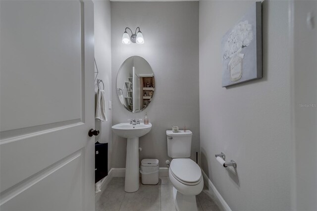 bathroom with toilet, baseboards, and tile patterned flooring