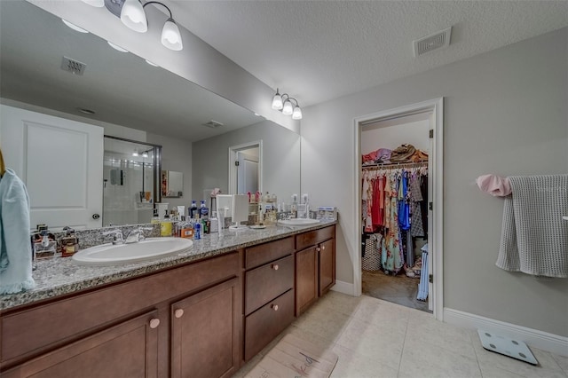 full bath featuring baseboards, a sink, a stall shower, and visible vents