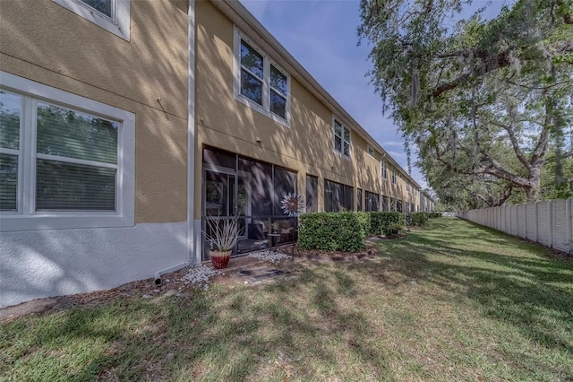 back of property with stucco siding, fence, and a yard