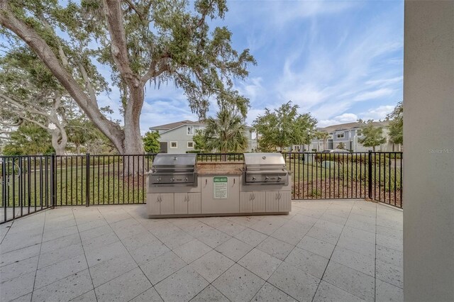 view of patio / terrace with a residential view, exterior kitchen, grilling area, and fence
