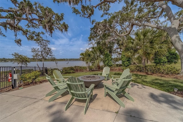 view of patio with fence, a water view, and a fire pit