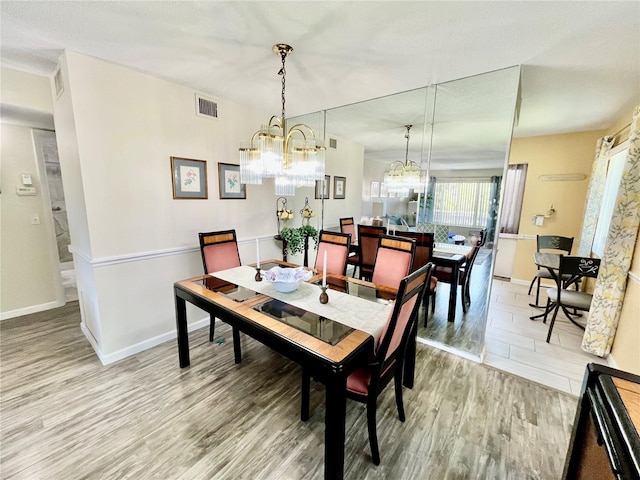 dining room featuring a chandelier, baseboards, visible vents, and light wood-style floors