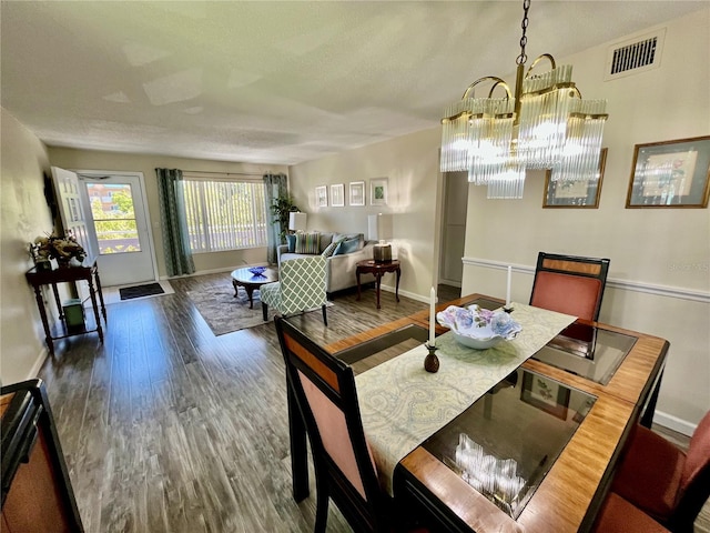 dining space with baseboards, a chandelier, wood finished floors, and visible vents