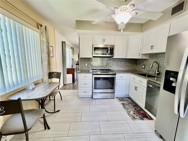 kitchen featuring a sink, stainless steel appliances, white cabinetry, tasteful backsplash, and visible vents