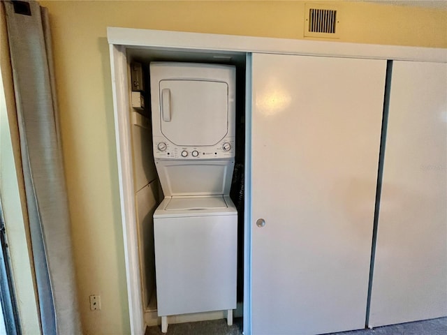 laundry area featuring stacked washer / drying machine, visible vents, and laundry area