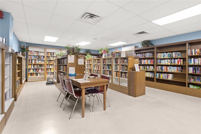 interior space with a drop ceiling, bookshelves, and visible vents