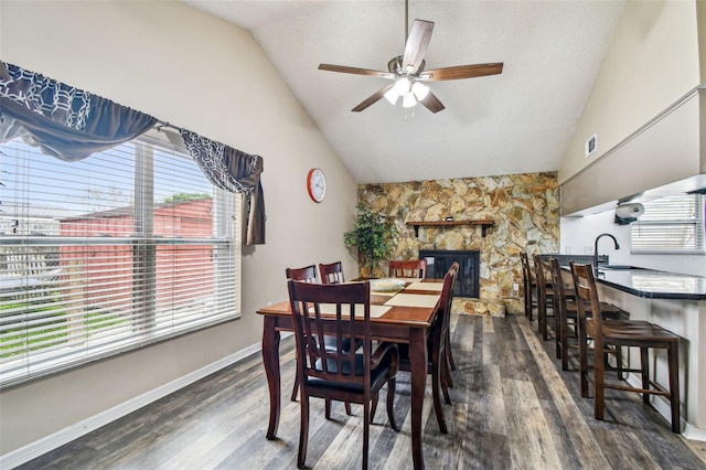 8225 Medford Dr, Port Richey, FL 34668 - dining room with lofted ceiling, wood finished floors, a ceiling fan, a fireplace, and baseboards