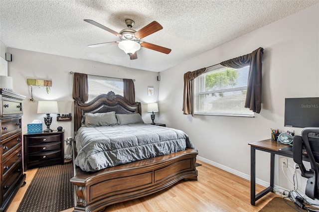 8225 Medford Dr, Port Richey, FL 34668 - bedroom with multiple windows, light wood-style floors, a textured ceiling, baseboards, and a ceiling fan