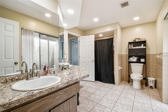 8225 Medford Dr, Port Richey, FL 34668 - full bathroom featuring toilet, a wainscoted wall, vanity, tile walls, and tile patterned flooring
