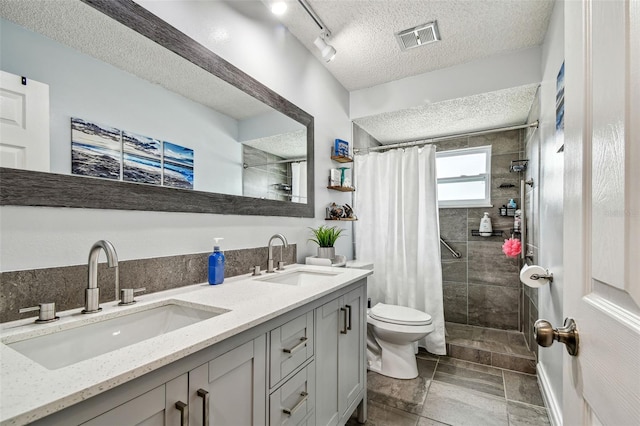 8225 Medford Dr, Port Richey, FL 34668 - bathroom featuring a textured ceiling, a tile shower, toilet, and double vanity