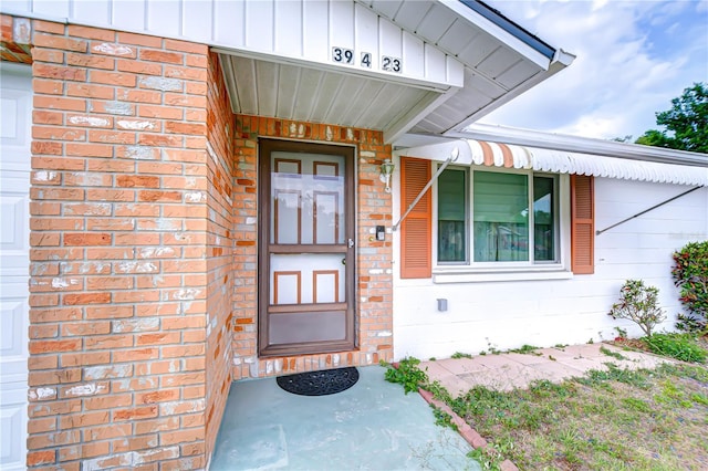entrance to property with board and batten siding and brick siding