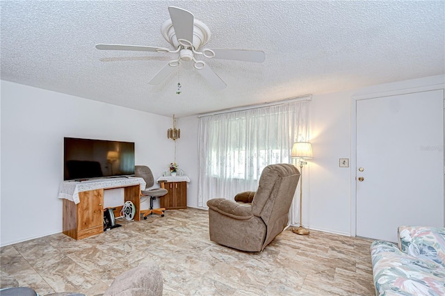 living room with a ceiling fan and a textured ceiling