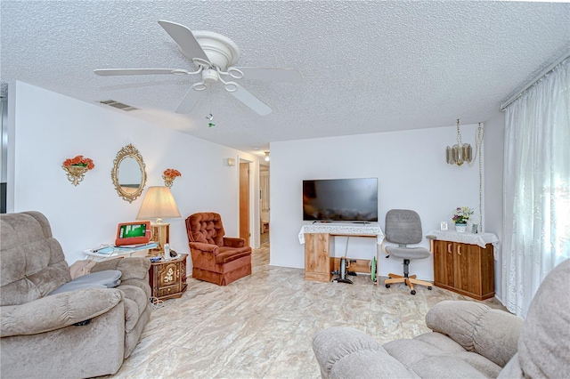 living area with a ceiling fan, a textured ceiling, and visible vents