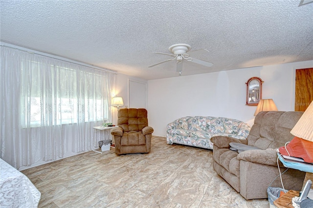 living area with a ceiling fan and a textured ceiling