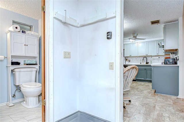 bathroom featuring decorative backsplash, a textured ceiling, visible vents, a sink, and toilet