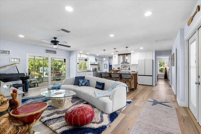 living room with recessed lighting, light wood-type flooring, and ceiling fan