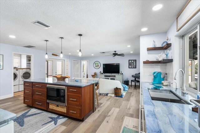 kitchen with built in microwave, a sink, separate washer and dryer, light wood finished floors, and open shelves